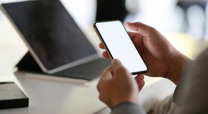 Cropped shot of young businessman looking at blank screen smartphone